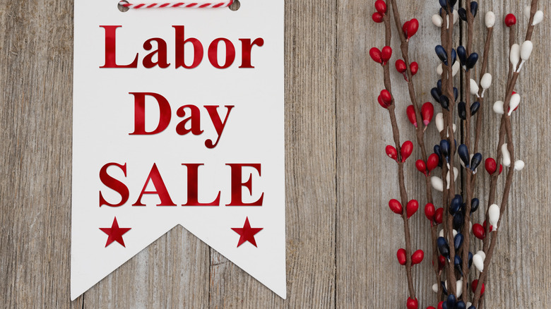A white sign advertising a Labor Day sale next to red, white and blue decorations