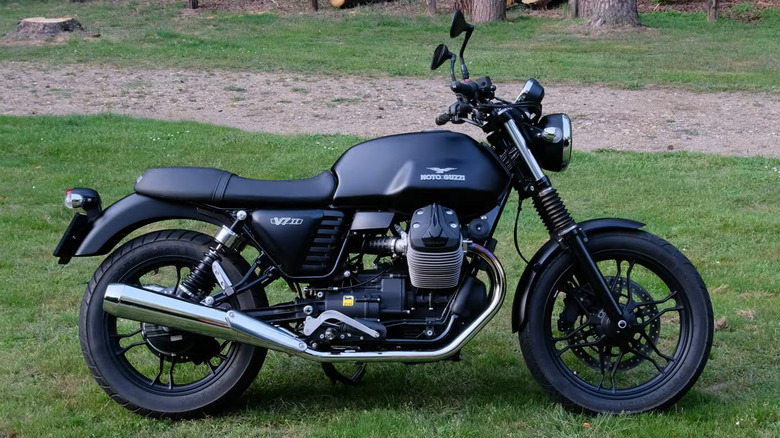 A Moto Guzzi V7 parked in a park on grass.