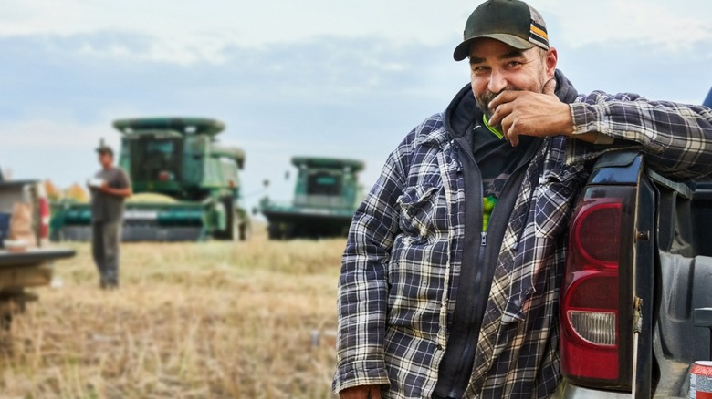 A man standing by his pickup truck on farm field
