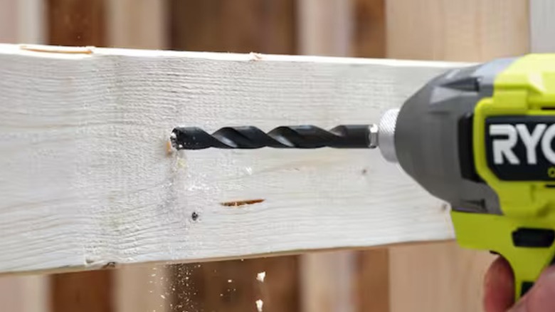 A person drilling wood with a Ryobi drill.