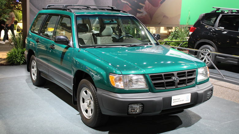 A green 1999 Subaru Forester parked on display at a car show, front 3/4 view