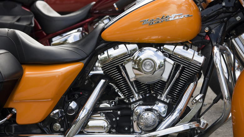 A closeup of an orange and chrome Harley Davidson Road King motorcycle with a Twin Cam 88 engine