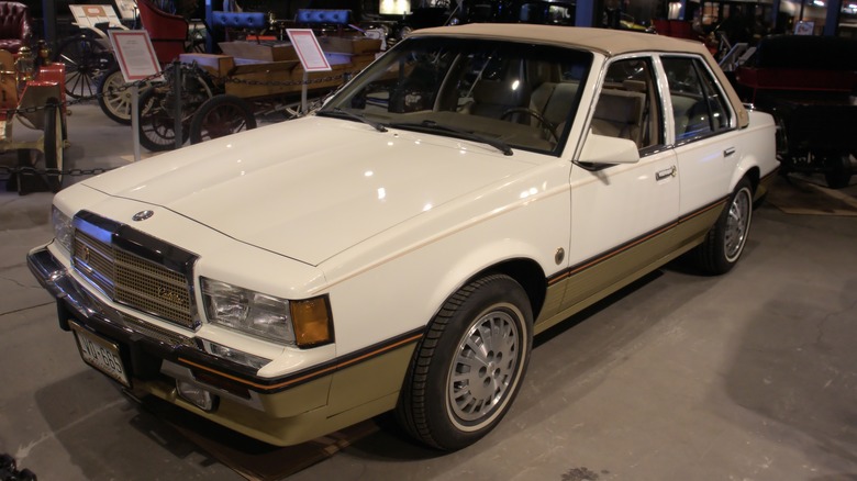 A white 1986 Cadillac Cimarron on display.