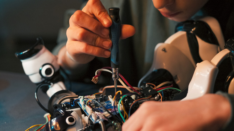 A person using a precision screwdriver on circuit board.