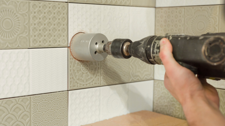 Using a drill to ctu a large hole on ceramic tiles, a job not meant for an impact driver.