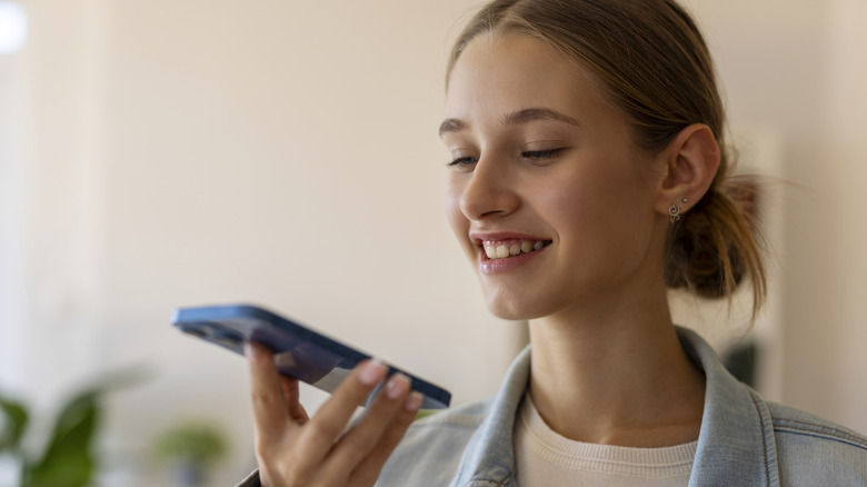 A person smiling while holding a smartphone