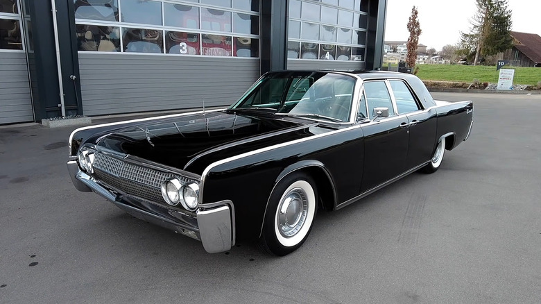 A 1961 Lincoln Continental in black outside a storage facility, front 3/4 view