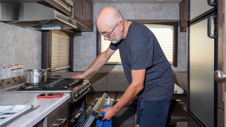 A man using the kitchen inside of an RV.