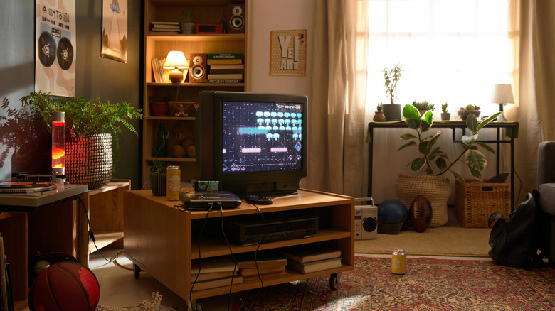 A living room with old-school technology, including a tube television, an old console gaming system, and a stereo