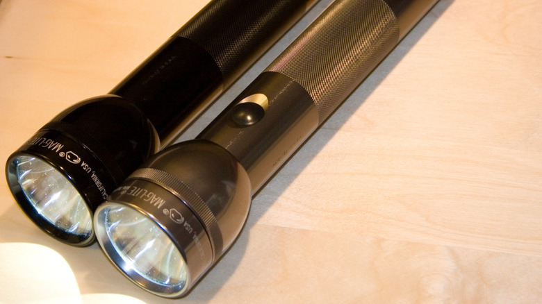 Two Maglite flashlights illuminated on a surface.