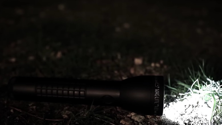 A Maglite flashlights illuminated on the ground.