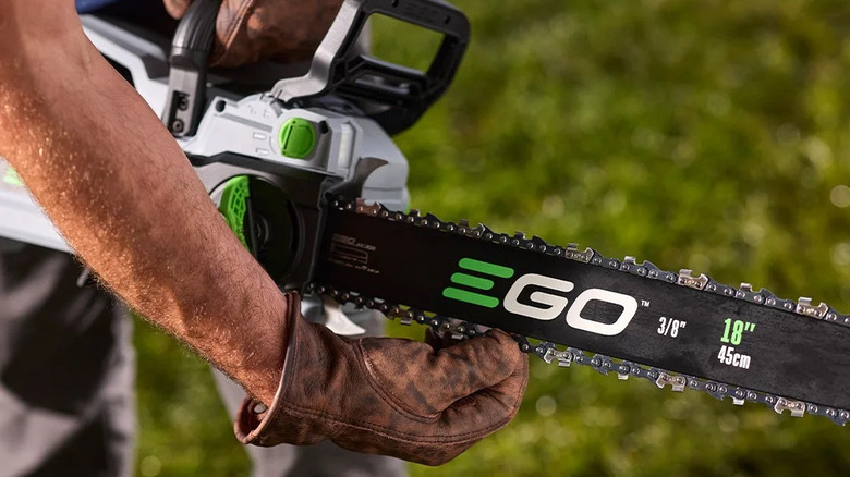 close-up of a person wearing leather gloves feeling the chain on an Ego Power Plus 18-inch chainsaw