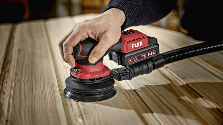 close-up of a worker using a Flex Ore 2-125 18-EC 18V orbital sander on a piece of wood