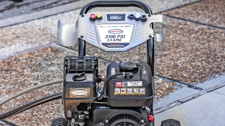 A Simpson PowerShot PS61254 pressure washer sitting on a concrete and gravel pathway