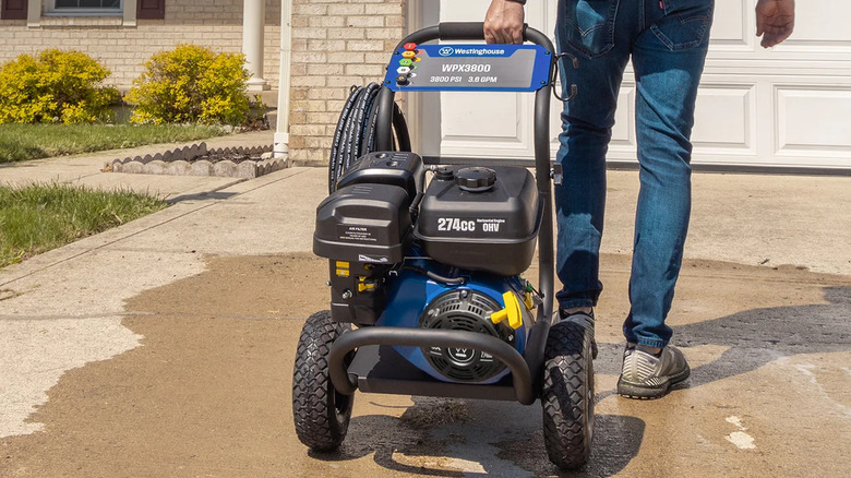 A man rolling a Westinghouse WPX3800 Pressure Washer on a home's driveway