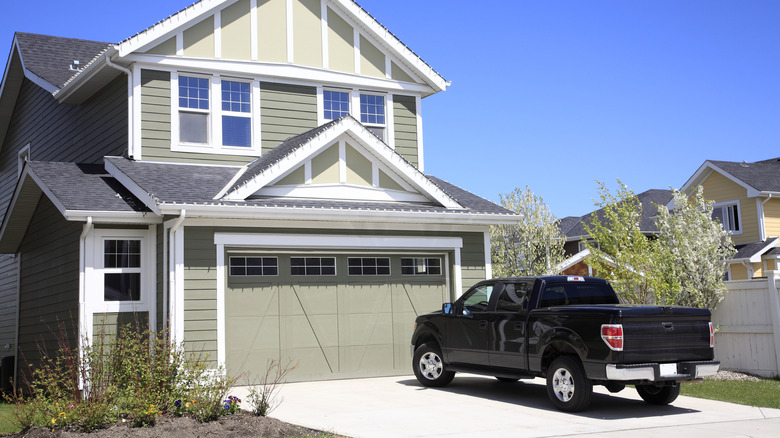 A black pickup truck parked in the driveway of a modern two-story home