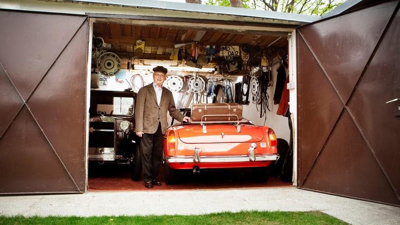 Old man standing beside car parked in garage