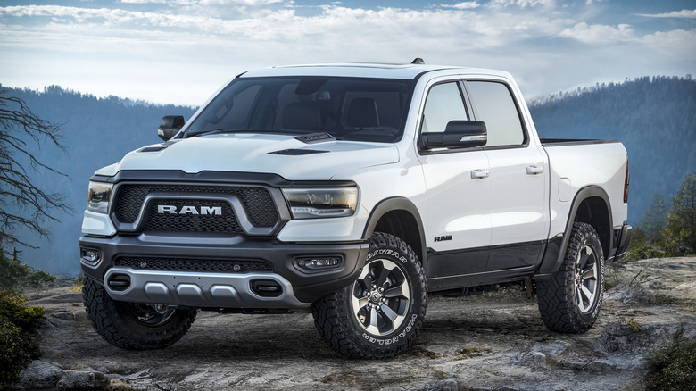 A white 2019 Ram 1500 Rebel on a rocky road, mountains in the back.