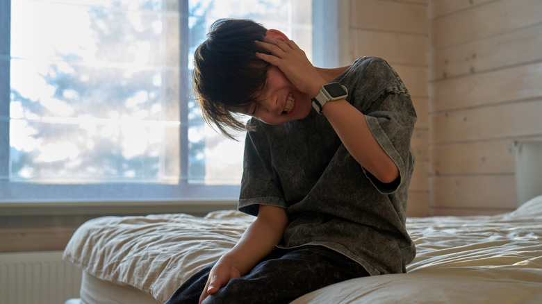 A child on a bed exhibiting ear pain.