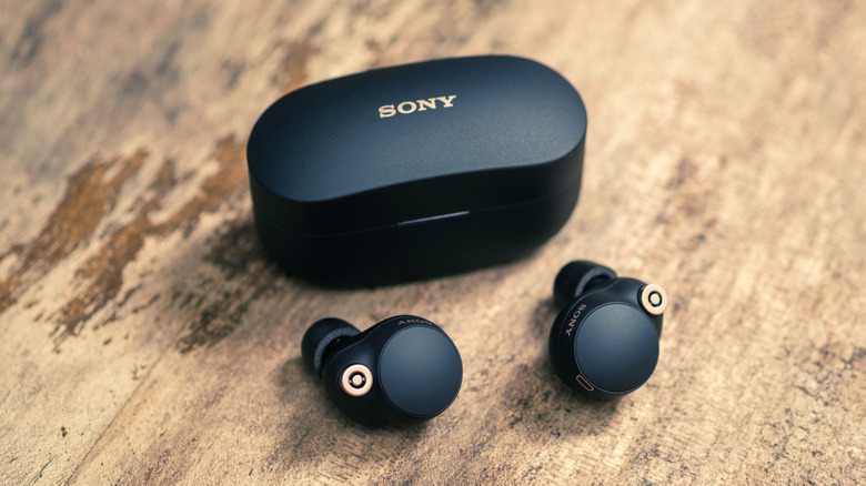 Sony earbuds and their case on a wood surface.