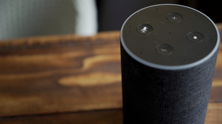 A black Amazon Echo with Alexa sitting on a wood table