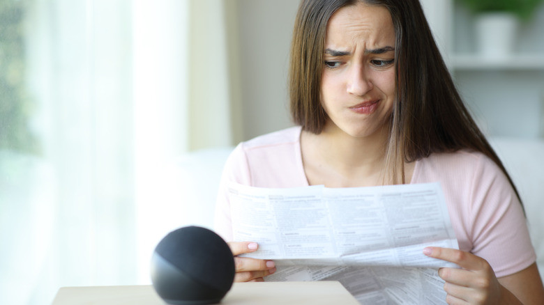 A woman making a confused expression while looking at a smart speaker