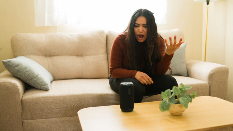 A women visibly frustrated with a smart speaker on a coffee table