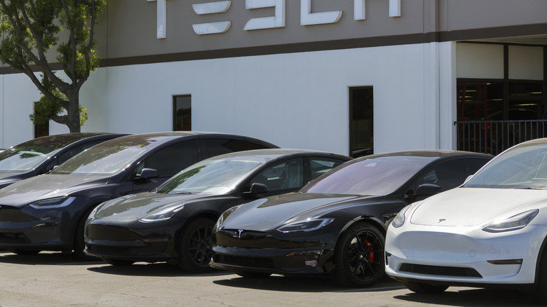 A row of Teslas parked in front of a Tesla dealership