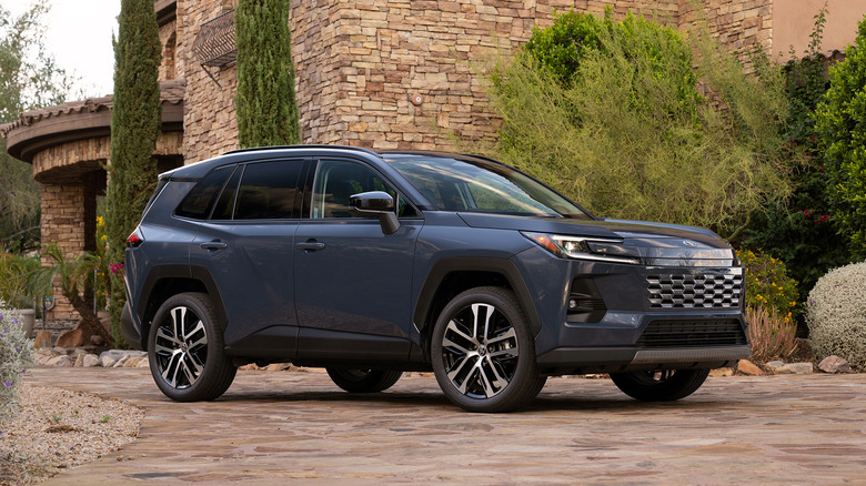 A blue 2026 Toyota RAV4 parked in front of a large stone building