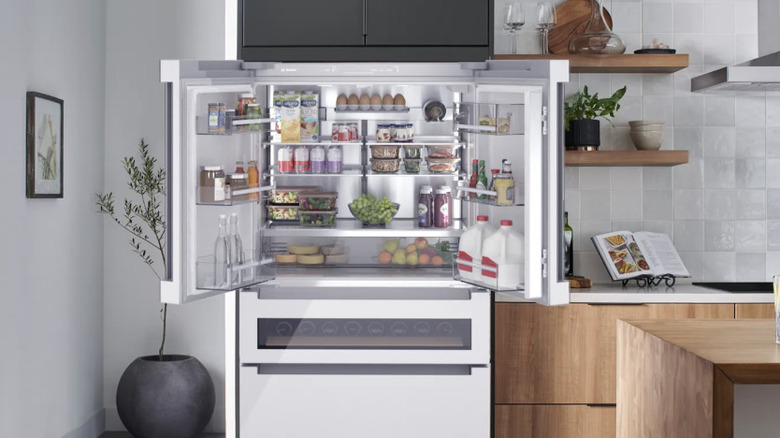 A white, high-end Bosch refrigerator with the French doors open in a clean kitchen