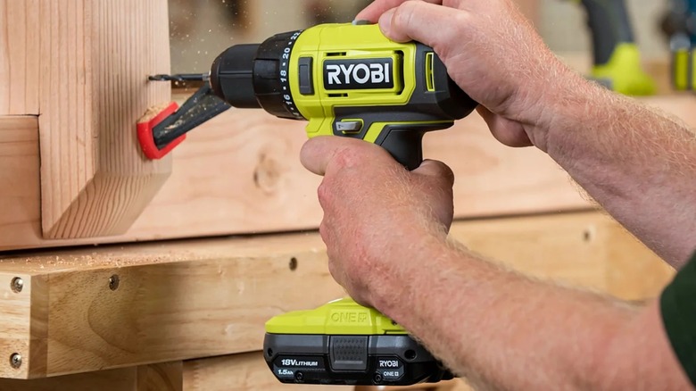 A person using a Ryobi drill on wood.