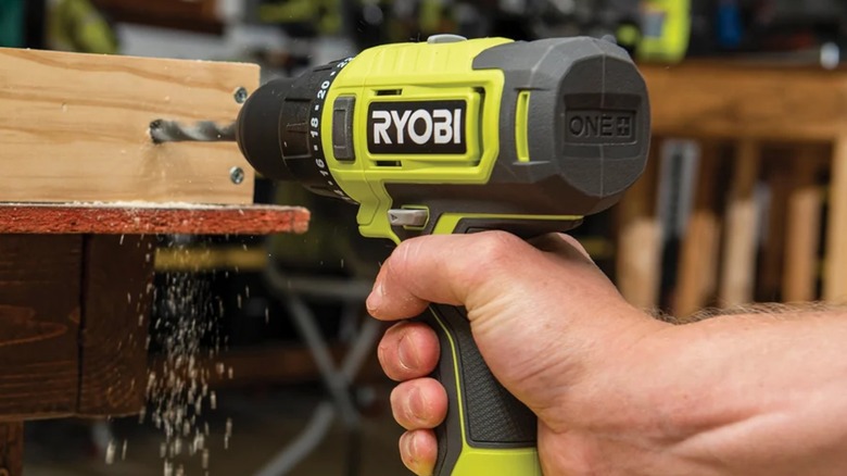 A person using a Ryobi drill on wood.