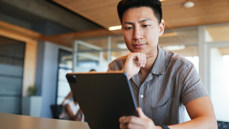 Young man intently examines a tablet