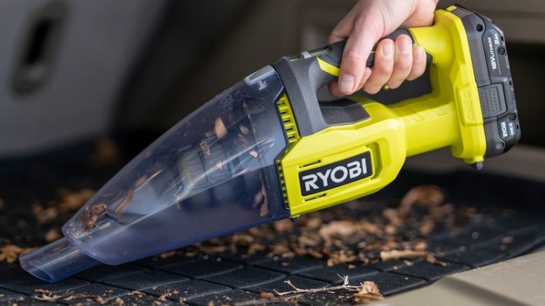 Close-up of a person sucking up dead leaves with Ryobi One 18V Multi-Surface Handheld Vacuum