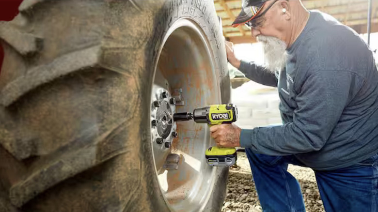 An older man using a Ryobi impact wrench on a large tire