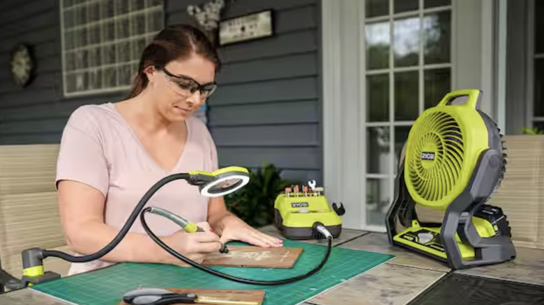 A woman at work outside with a Ryobi fan on her work surface