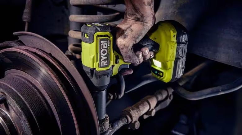 Hand holding 18V ONE+ HP Compact Brushless 1/4 in. Impact Driver and using it inside machine