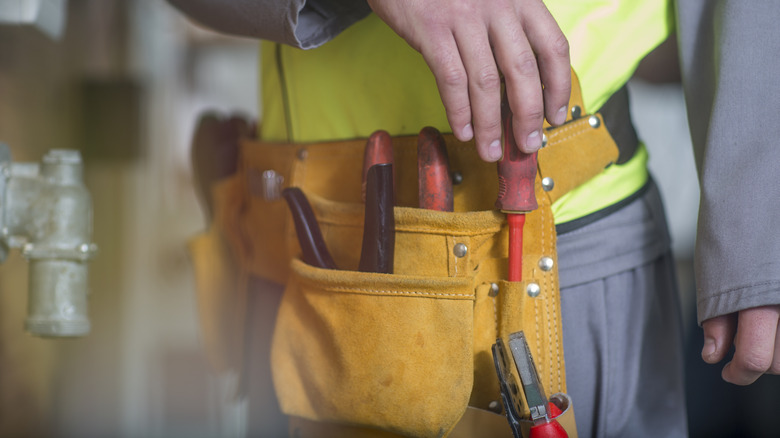 Worker getting tool from tool belt