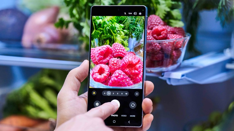 Person taking a photo of raspberries using a Samsung Galaxy S25 Ultra
