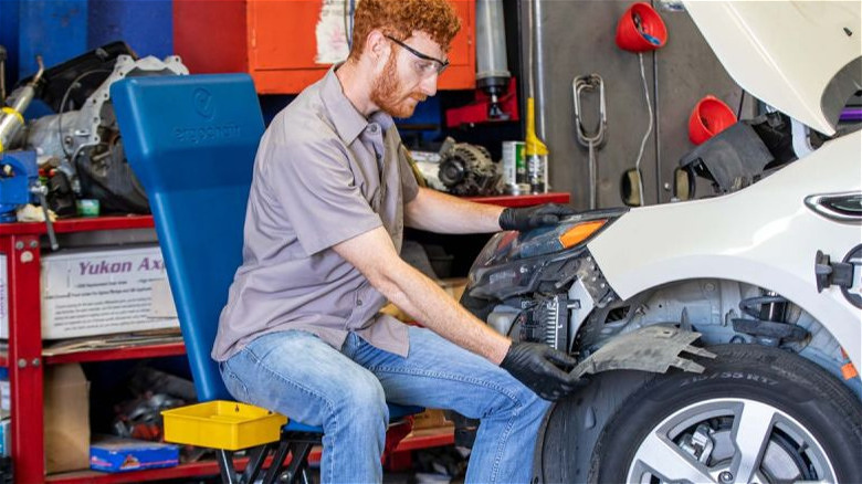 A person sitting on the Ergochair ERGO-RS while working on a vehicle