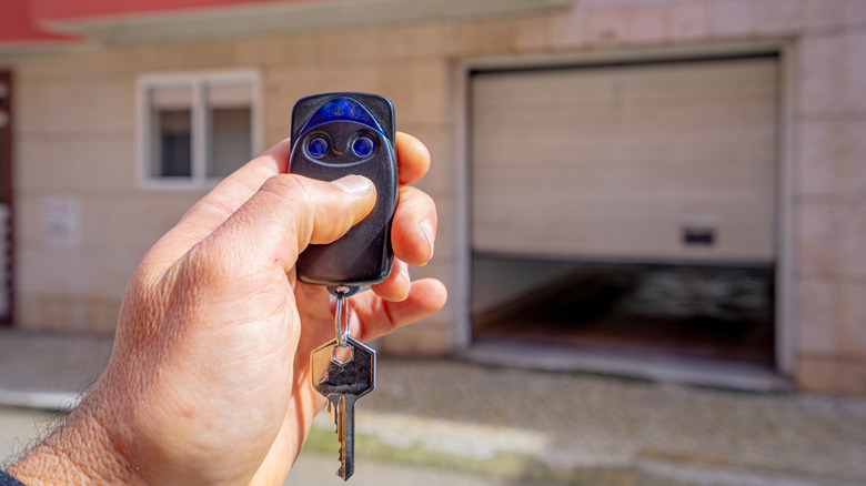 Close-up of hand pressing button on keychain garage door opener.