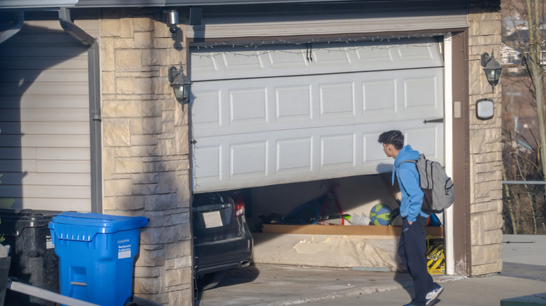 Man standing near half-open garage door.