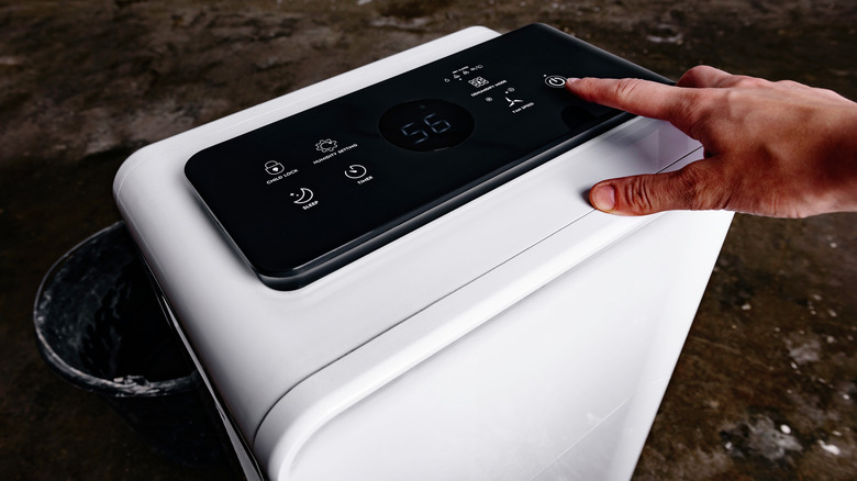Person turning on a dehumidifier in a garage