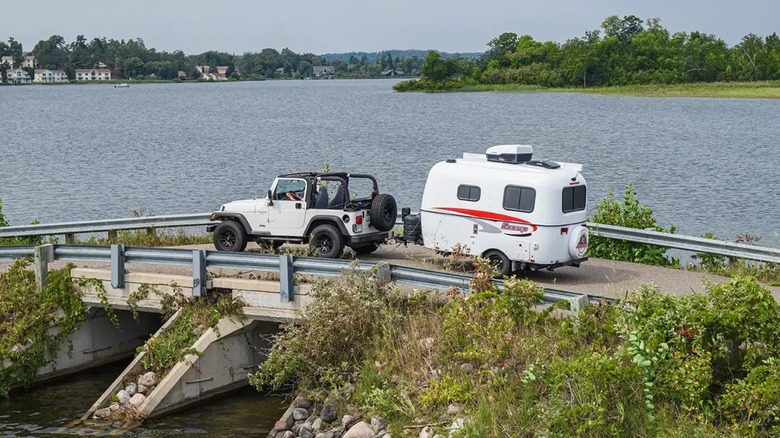 A Jeep towing a 13ft Scamp across a bridge