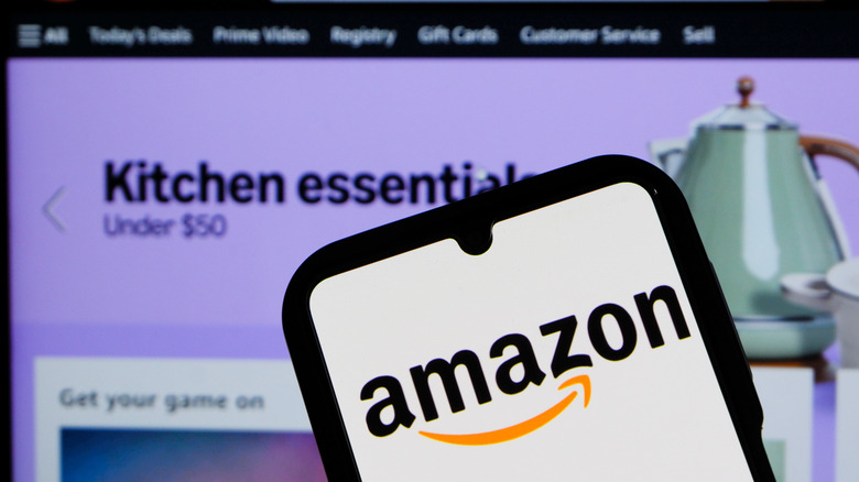 Amazon logo on smartphone with desktop site in background