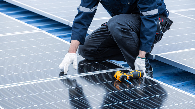 Person servicing solar panels on a roof.