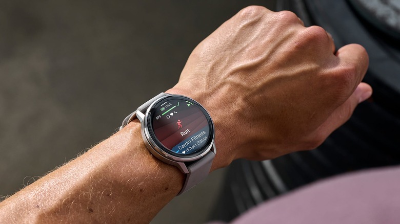 A person wears a Garmin Venu 4 displaying running and fitness tracking information.