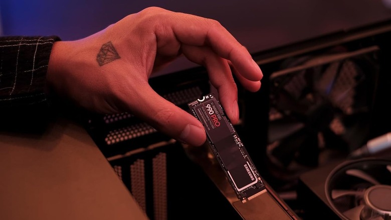 A picture of a man installing a samsung 990 pro ssd into a pc