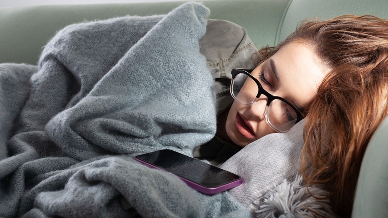Person asleep on couch next to smartphone