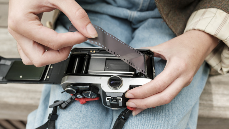 A person carefully loading film into an older camera